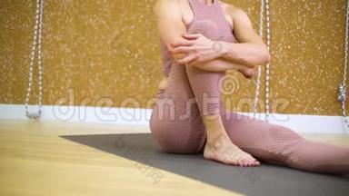 年轻女子坐在垫子上，在<strong>瑜伽馆伸展</strong>身体